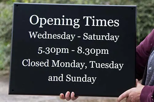White on black is a very visable combination Painted Opening Times Sign