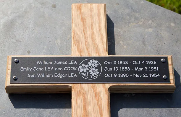 Black engraved plaque on wooden cross