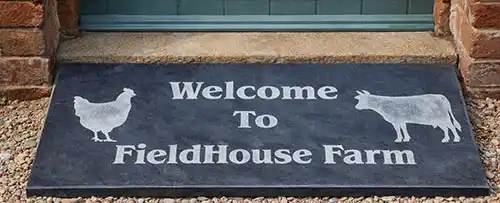 Engraved slate doorstep Welcome to FieldHouse Farm with sandblasted lettering and farm animal motifs