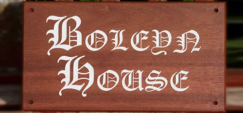Sapele house sign with white text