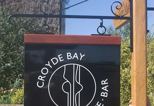 Three different materi are available for the sign itself.als A metal hanging sign with a hardwood header.