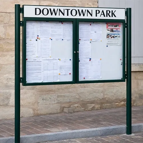Outdoor notice board with posts and header panel in town setting